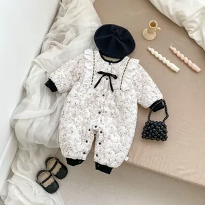 Detailed flat lay of a floral quilted baby romper with lace trim and black bow details