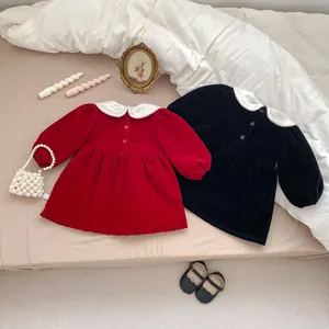 Detail of red and black velvet toddler dresses featuring Peter Pan collars and buttons