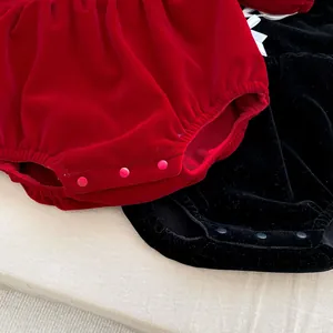 Detail view of velvet baby romper snap buttons and thick fabric texture in red and black