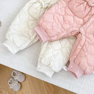 Close-up of quilted floral baby rompers with ribbed cuffs and snap button detail