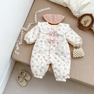 Detail of floral baby romper featuring lace collar, pink bows, and quilted texture