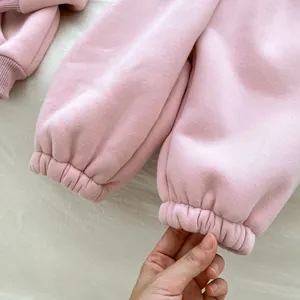 Detailed close-up of ribbed cuffs on thick fleece-lined pink winter suit for baby girls
