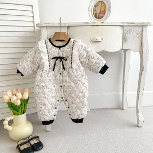 Detailed close-up of floral quilted baby romper with lace collar and black bow accents