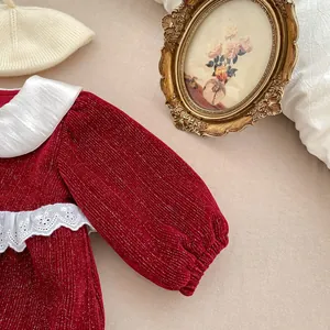 Close-up of baby girl velvet festive romper with white lace collar and glitter fabric