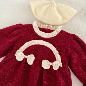 Detail eines roten Baby-Winterkleides mit weißen Rüschen und Samttextur