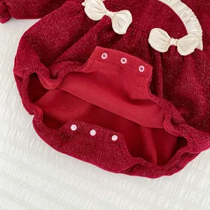 Detail eines roten Baby-Fleece-Einteilers mit Samtstruktur, Glitzer und Druckknöpfen
