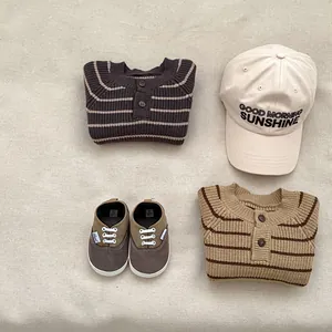 Plano detalle de cárdigan de punto a rayas, gorra beige y zapatos de lona marrones