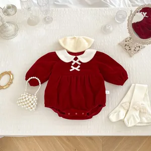 Detail view of red velvet baby bodysuit with Peter Pan collar and bow on white background