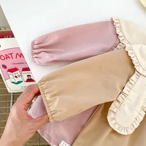Detail of toddler girls' pink and beige ruffled collar top with soft cotton texture