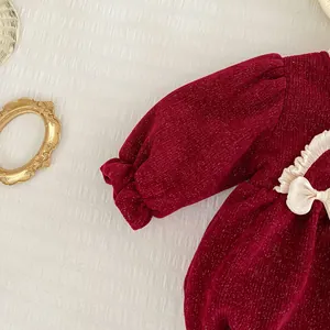 Detail eines weinroten Babykleids aus Cord mit Goldfäden und Satin-Schleifendekoration