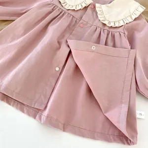 Detailed close-up of pink cotton cardigan with white ruffle collar and size 73 label