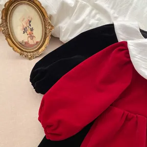 Flat lay of velvet girls' dresses in red and black with white Peter Pan collars