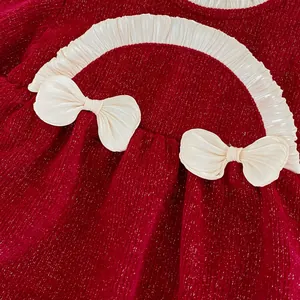 Detail eines roten Baby-Bodys mit weißen Rüschen und zwei Satin-Schleifen-Dekorationen