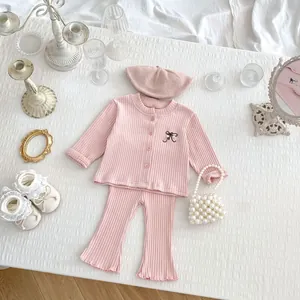 Flat lay of pink knit toddler outfit with bow embroidery, beret, and flared pants