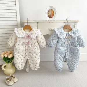 Close-up of floral quilted baby rompers with lace collars and bow details in cozy home setting