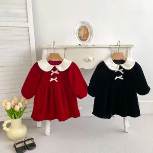 Detail of velvet girl dresses with bow collars in red and black colors