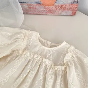 Détail d'une blouse bébé fille avec broderie florale, volants et texture coton