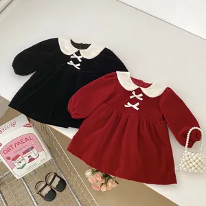 Detail view of velvet girls' dresses in black and burgundy with white bows and collars