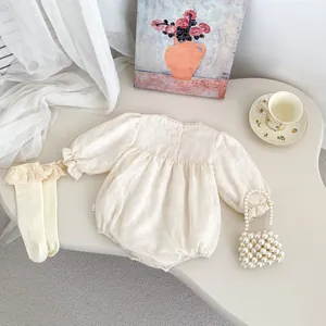 Detail of baby long-sleeve bodysuit with floral embroidery and lace trim on cream fabric