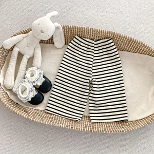 Vue à plat du pantalon rayé pour enfant avec chaussures en dentelle dans un berceau