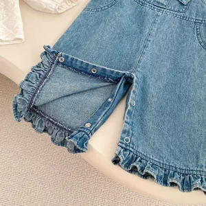 Détail de l'entrejambe à pressions et ourlet volanté sur salopette en jean pour bébé