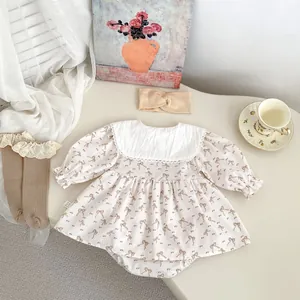 Vue à plat d'une robe barboteuse pour bébé avec broderie noeud, bandeau et chaussettes