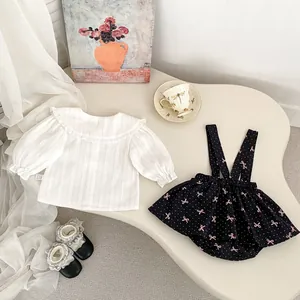 Détail à plat d'une tenue bébé fille avec haut à volants et robe à pois bleu marine