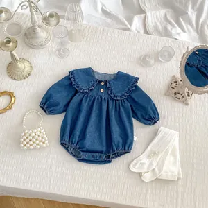 Détail du body bébé en denim bleu foncé avec grand col à volants et boutons en bois