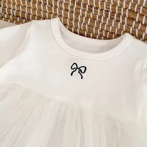 Nahaufnahme eines weißen Baby-Baumwollkleides mit schwarzer Schleife und Tüll-Rock