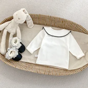 Details des weißen Baby-Langarmshirts mit Vintage-Kragen und schwarzer Wellenspitze