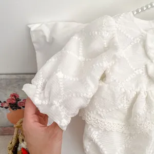 White baby girl bodysuit with floral embroidery, puff sleeves and lace details on a hanger