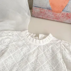 Gros plan d'une blouse blanche en dentelle pour fille avec broderies et col à volants