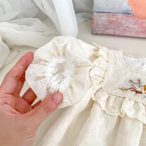 Close-up of floral embroidery and hollowed-out lace details on a baby girl romper