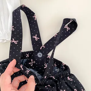 Détail de la jupe à bretelles pour bébé avec pois, nœuds roses et taille élastique