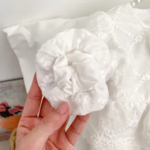 Close-up of baby romper sleeve featuring delicate lace ruffles and floral embroidery