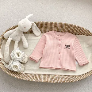 Detail of pink ribbed knit baby top with bow embroidery and size 66 label on knit fabric