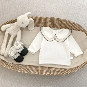 Detailaufnahme der Babybluse mit weißem Peter-Pan-Spitzenkragen und schwarzem Wellenrand