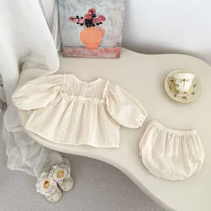 Détail de la broderie florale sur chemise crème à manches longues et culotte pour bébé
