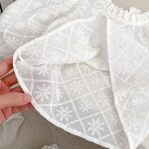 Détail d'un haut blanc pour fille avec broderie florale et texture à volants doux