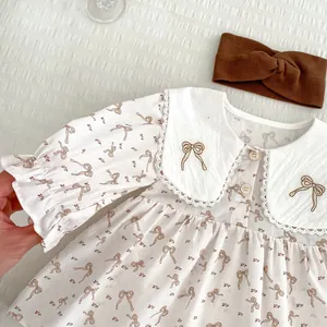 Détail de la barboteuse bébé avec broderie nœud sur col en dentelle et boutons en bois