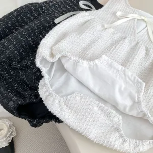 Details des Tweed-Babybodys mit Satinschleifen und praktischen Druckknöpfen für einfaches Wickeln