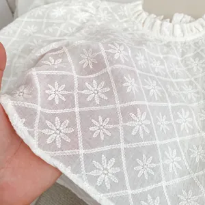 Gros plan sur le tissu brodé à fleurs blanches pour ensemble salopette fille