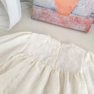 Close-up of white baby bodysuit featuring delicate floral embroidery and lace collar detail