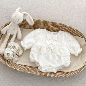 Detailed view of white baby romper with 3D diamond texture, lace edges, and matching shoes