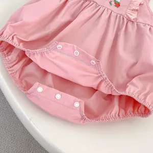 Detail of pink cotton baby bodysuit featuring strawberry embroidery and bottom snap buttons