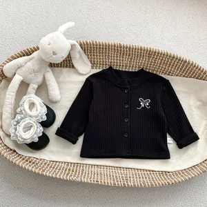 Detail of baby black ribbed cardigan with white bow embroidery and lace toddler shoes