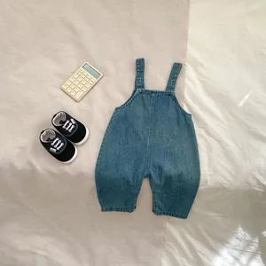 Détail de la salopette en jean bleu pour bébé avec larges bretelles et texture souple