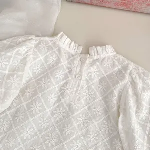 Détail du haut brodé blanc à manches longues avec col à volants et broderies florales