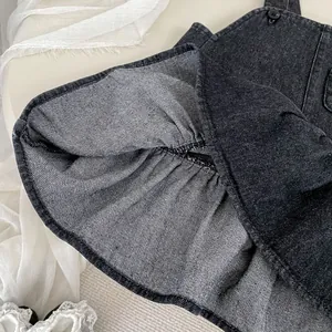 Detailansicht des schwarzen Jeans-Trägerkleids mit Knöpfen und feinen Nähten