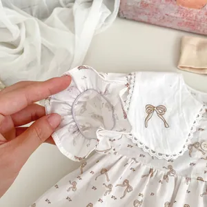 Détail de la manchette élastique volantée et col en dentelle sur robe bébé à nœuds